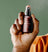 Close-up of a hand holding and spraying a Meridian branded deodorant spray bottle against a green background.
