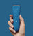 Hand holding blue rechargeable electric hair clipper with power button and LED indicators on solid blue background