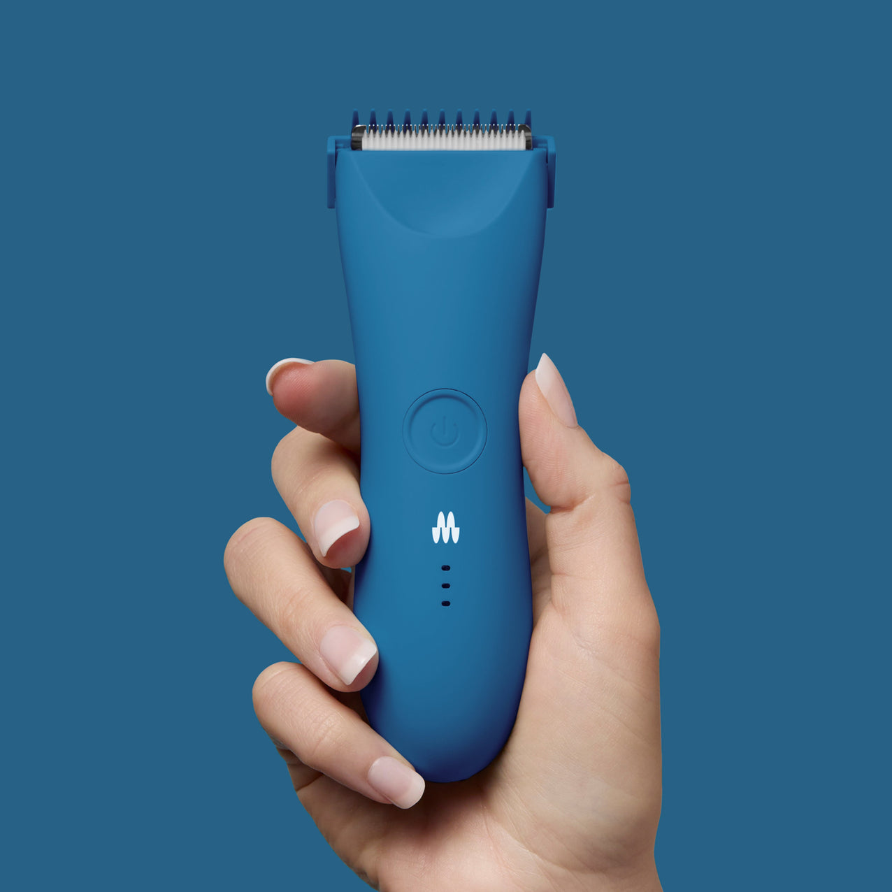 Hand holding blue rechargeable electric hair clipper with power button and LED indicators on solid blue background