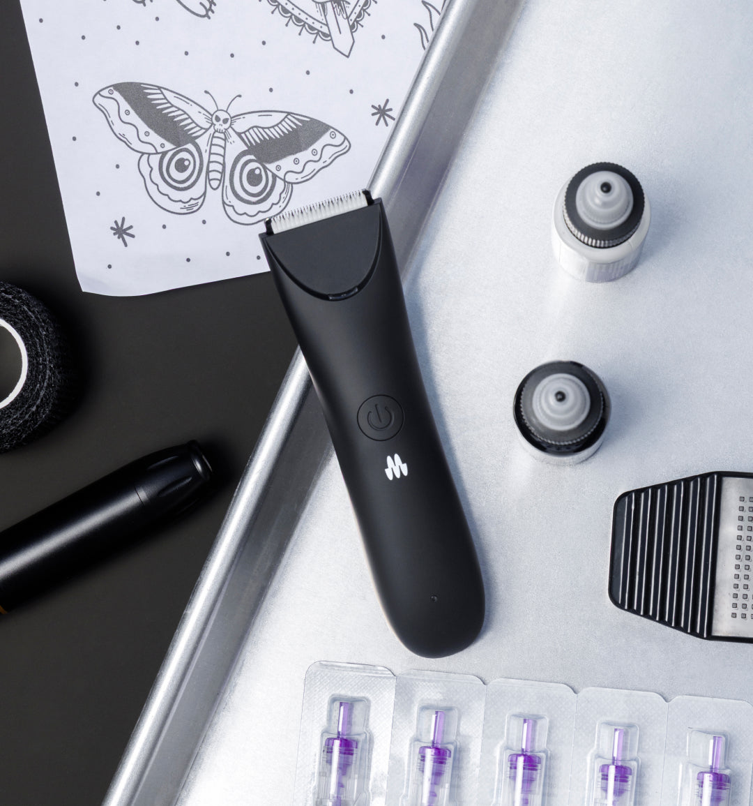 Professional black electric hair clipper with replacement blades, clipper comb, tattoo stencil, and black ink for barber tools.