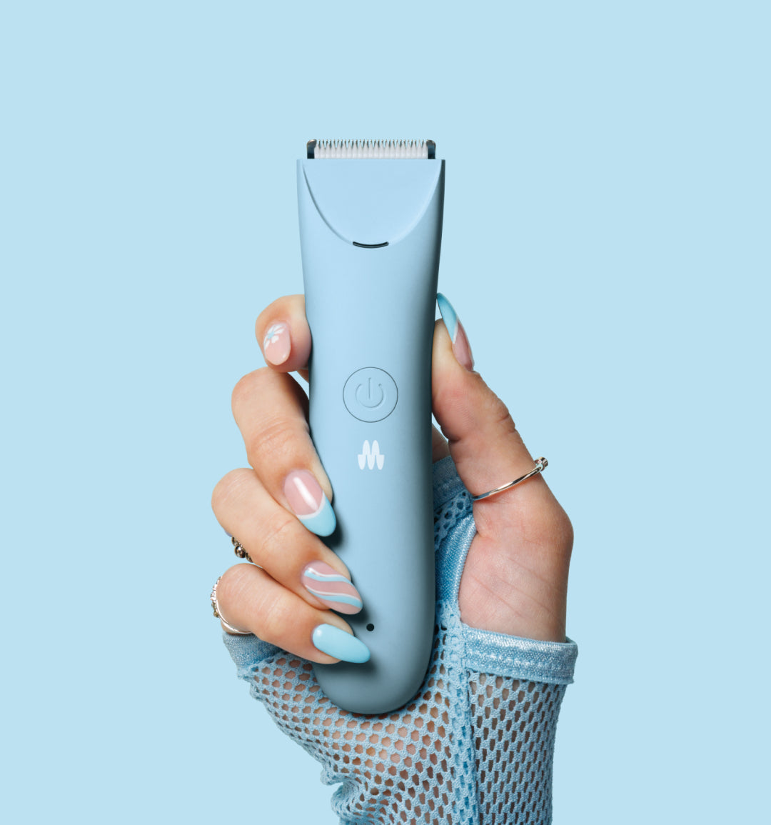 Light blue electric hair trimmer held by manicured hand with rings against light blue background