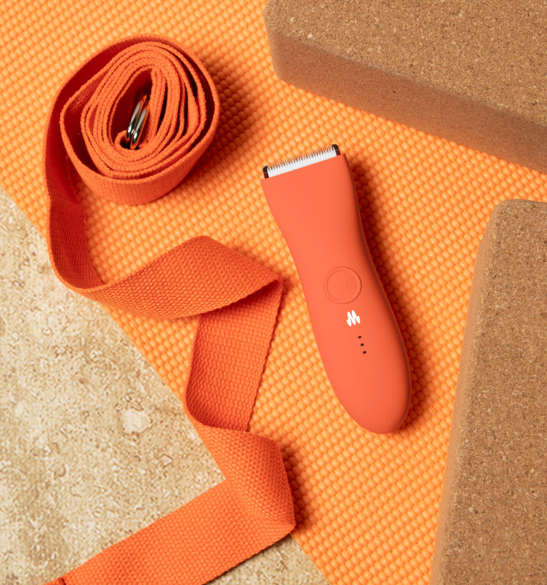 Orange yoga strap, cork yoga blocks, and textured orange yoga mat arranged for fitness and stretching exercises.