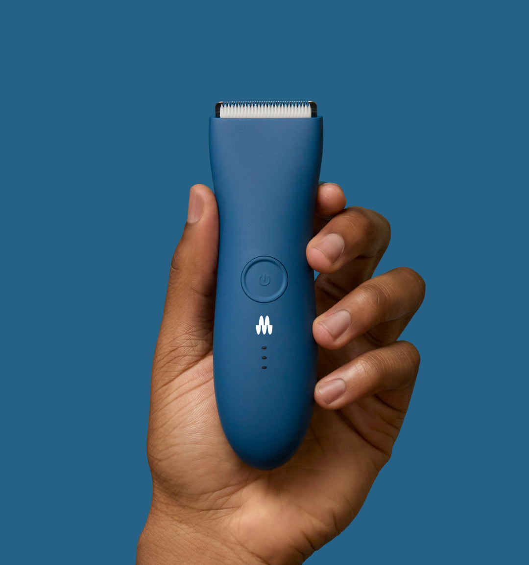 Hand holding sleek blue electric hair trimmer with white blade on blue background